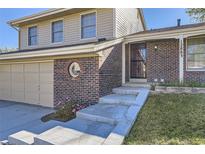 Brick and beige two-story home with attached garage and landscaping at 12883 Columbine Cir, Thornton, CO 80241