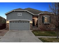 Charming stucco and stone home featuring a two-car garage and well-maintained landscaping at dusk at 25148 E Lake Pl, Aurora, CO 80016