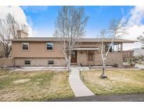 Charming two-story home with a brick and stucco exterior, mature trees, and a well-manicured lawn at 1095 Lake Woodmoor Dr, Monument, CO 80132