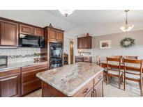 Spacious kitchen featuring custom wood cabinets, a center island, and stone countertops at 1095 Lake Woodmoor Dr, Monument, CO 80132