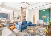 Bright and airy living room featuring exposed beams, hardwood floors, and a modern blue sectional at 1501 Wazee St # 4B, Denver, CO 80202