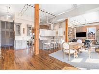 Bright open-concept living area with hardwood floors, exposed brick, and dining area is ideal for modern living at 1501 Wazee St # 4B, Denver, CO 80202