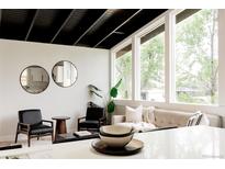 Bright living room with modern decor, black ceiling beams, and large windows with view at 7918 Raleigh Pl, Westminster, CO 80030