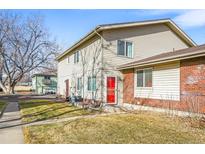 Traditional townhome with a brick accent, trimmed lawn, and mature shade tree at 3355 S Flower St # 59, Lakewood, CO 80227