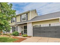 Two-story home featuring white brick, an attached garage, manicured shrubs, and a well-kept green lawn at 16051 E Alabama Dr, Aurora, CO 80017