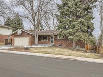 Charming home showcasing a brick and wood exterior, attached garage, and a well-maintained front yard at 7016 Reed St, Arvada, CO 80003