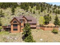 View of home featuring natural wood siding, decks, natural landscaping, and mature trees at 33095 Bergen Mountain Rd, Evergreen, CO 80439