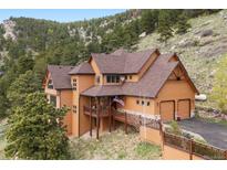 Charming home with a warm exterior, attached garage, and lovely balcony surrounded by lush trees and mountain views at 33095 Bergen Mountain Rd, Evergreen, CO 80439