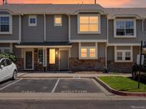 Charming townhome exterior with gray siding, stone accents, and visitor parking at sunset at 9024 Gale Blvd # 3, Thornton, CO 80260