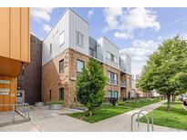 Modern multi-level condo building with brick facade, metal accents, and professional landscaping at 2550 Lawrence St # Rb306, Denver, CO 80205