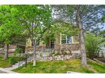 Charming home exterior with stone accents, manicured lawn, mature trees, and inviting front porch at 7193 S Versailles Way, Aurora, CO 80016