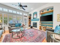 Cozy living room with a fireplace, built-in shelves, and large windows at 7193 S Versailles Way, Aurora, CO 80016
