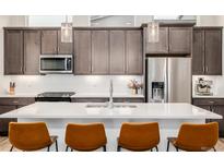 Modern kitchen with stainless steel appliances, a white countertop island, and pendant lighting at 6776 Navajo Way, Denver, CO 80221