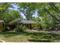 Quaint backyard with lush greenery, colorful flowers, and a charming covered patio at 901 S Leyden St, Denver, CO 80224
