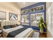 Bright bedroom featuring large windows, a cozy bed, and a stylish blue accent wall at 4084 S Carson St # A, Aurora, CO 80014