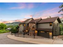 Stunning two-story home features a stone turret, fenced yard, and beautiful mountain views at sunset at 600 Cascade Dr, Golden, CO 80403