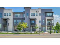 Modern townhome exterior with a combination of gray siding and stone accents, plus manicured landscaping at 1575 W 68Th Ave, Denver, CO 80221