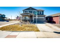 Charming two-story home with a well-manicured front yard on a sunny day with a two car garage at 397 Maple St, Bennett, CO 80102