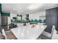 Kitchen with stainless steel appliances, white cabinets, contrasting countertops, and large center island at 2650 S Vaughn Way # D, Aurora, CO 80014