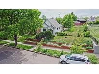 Charming home featuring a well-manicured lawn, flower beds, mature trees, and a quaint facade at 2809 Yates St, Denver, CO 80212