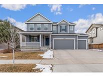 Two-story house with gray siding, a large front porch, and a two-car garage at 12243 Joplin St, Commerce City, CO 80603