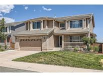 Charming two-story home with landscaped yard, tan siding, brick accents, and tan tile roof at 6511 Shea Pl, Highlands Ranch, CO 80130