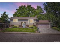 Charming two-story home with a well-maintained lawn, mature trees, and attached garage at 7331 S Webster St, Littleton, CO 80128