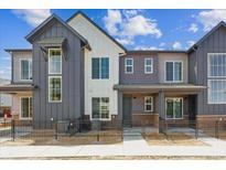 Modern townhouse with gray and white facade, black accents, and small fenced front yard at 6882 Huddersfield Ln, Castle Pines, CO 80108