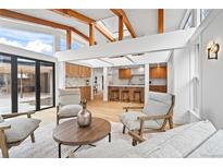 Bright living room featuring wooden beams, hardwood floors, and view to the kitchen and the outdoor patio at 456 Cherry Street, Denver, CO 80220