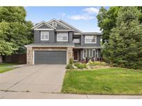 Charming two-story home with stone accents, gray siding, manicured lawn and two car garage at 2249 Weatherstone Cir, Highlands Ranch, CO 80126