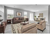 Bright living room featuring a brown leather sofa, decorative rug, and a dining area with seating for six at 7977 S Kittredge St, Englewood, CO 80112