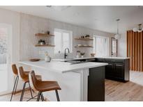 Modern kitchen featuring a waterfall island, floating shelves and updated appliances at 3400 Moore St, Wheat Ridge, CO 80033