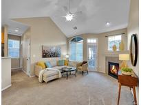 Bright living room with a cozy fireplace, high ceilings, and large windows at 1358 Carlyle Park Cir, Highlands Ranch, CO 80129