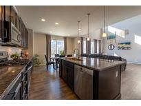 Open kitchen with dark cabinets, granite counters, stainless steel appliances, and seamless flow to the living area at 26960 E Costilla Dr, Aurora, CO 80016