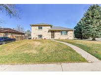 Charming two-story home boasts a well-manicured lawn and a welcoming walkway, complemented by mature trees at 2488 S Zurich Ct, Denver, CO 80219
