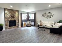 Bright living room boasts a stone fireplace, a white sofa, and a large bay window for ample natural light at 21 Douglas N Dr, Broomfield, CO 80020