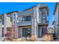 Modern three-story home with a stone facade, balcony, and a red front door at 6018 Beeler Ct, Denver, CO 80238