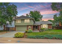 Charming two-story home with green siding, brick accents, a two-car garage, and manicured landscaping at 8116 W Fremont Dr, Littleton, CO 80128