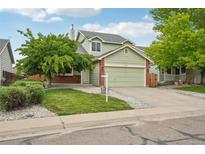 Charming two-story home with a well-manicured lawn, mature trees, and an attached two-car garage at 2427 Cherry Cir, Brighton, CO 80601