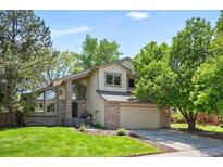Charming two-story home with a well-manicured lawn, mature trees, and attached two car garage at 7582 Powderhorn Dr, Lone Tree, CO 80124