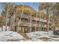 Three-story exterior featuring multiple balconies surrounded by trees and snow-covered ground at 1941 Boreas Pass Rd # 1C, Breckenridge, CO 80424