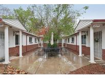 Charming courtyard featuring a table and seating between buildings with brick and white pillars at 4072 Ames St, Wheat Ridge, CO 80212