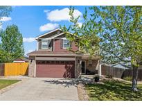 Charming two-story home featuring a two-car garage and manicured lawn in a suburban neighborhood at 13884 Lilac St, Thornton, CO 80602
