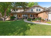 Charming two-story home with a lush green lawn, a brick facade, and a welcoming front porch with seating at 7830 W Friend Pl, Littleton, CO 80128