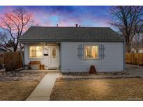 Charming home featuring a well-manicured lawn, stone details, and a cozy front porch under a colorful twilight sky at 935 Newark St, Aurora, CO 80010