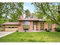 Charming brick home with a two-car garage and a well-manicured lawn surrounded by mature trees at 12193 W New Mexico Pl, Lakewood, CO 80228