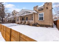 Charming brick home with covered front porch and snowy front yard at 2649 N High St, Denver, CO 80205