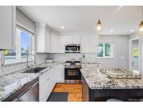 Bright kitchen features granite counters, stainless steel appliances, white cabinets, and hardwood floors at 6924 S Albion St, Centennial, CO 80122