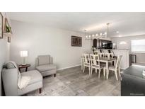 Bright living room featuring modern gray furniture and wood-look flooring adjacent to the dining area at 6450 Tennyson St # 1, Arvada, CO 80003