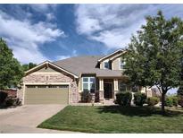 Charming home showcasing a stone facade, a manicured lawn, and a spacious two-car garage at 581 N Flat Rock Cir, Aurora, CO 80018